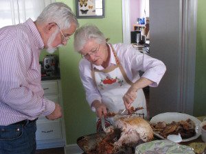 Theresa's mother-in-law carves the Thanksgiving turkey in her kitchen while her husband John supervises. 