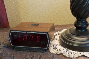 An alarm clock displaying the word "late". This could mean late for work, late for school, late for an appointment or meeting, etc.