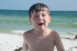 Elliott, at the beach in July. His cheek scar is still visible, and he now has a matching one on his forehead!